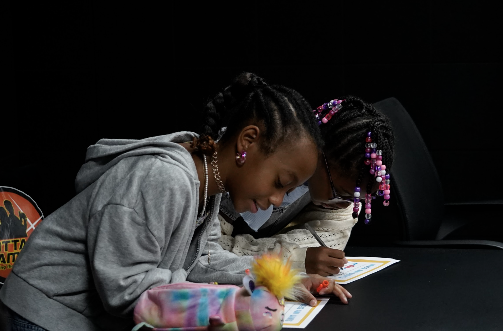 Two young StackCon attendees leaning over a table, focused on filling out their activity worksheets