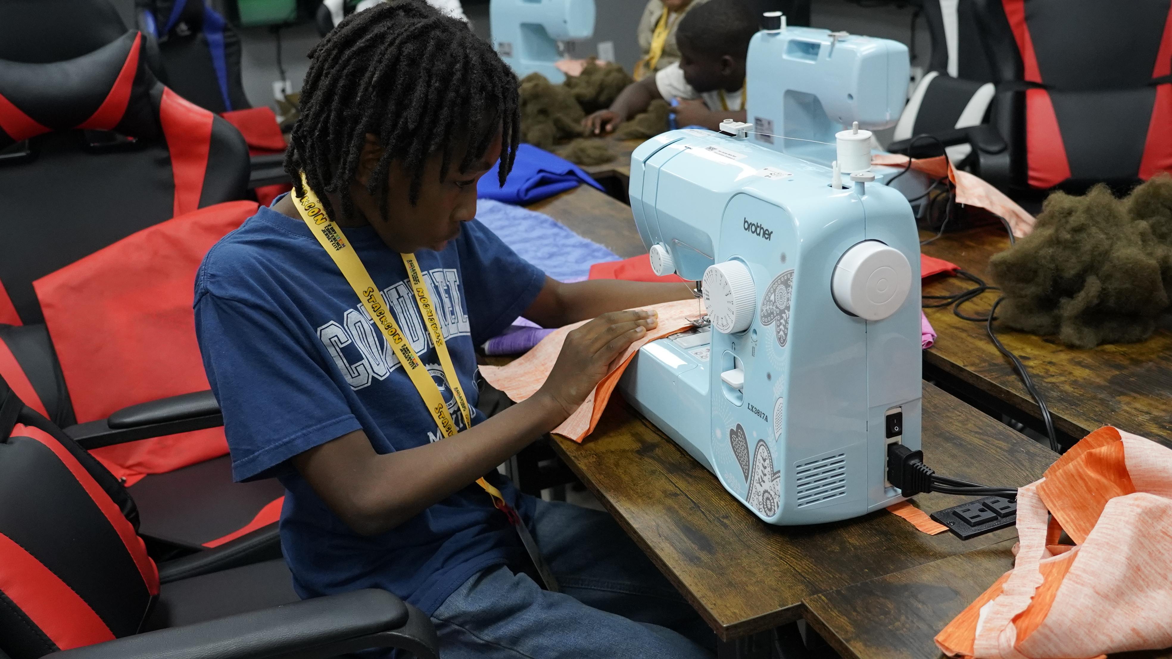 A student sewing fabric on a sewing machine