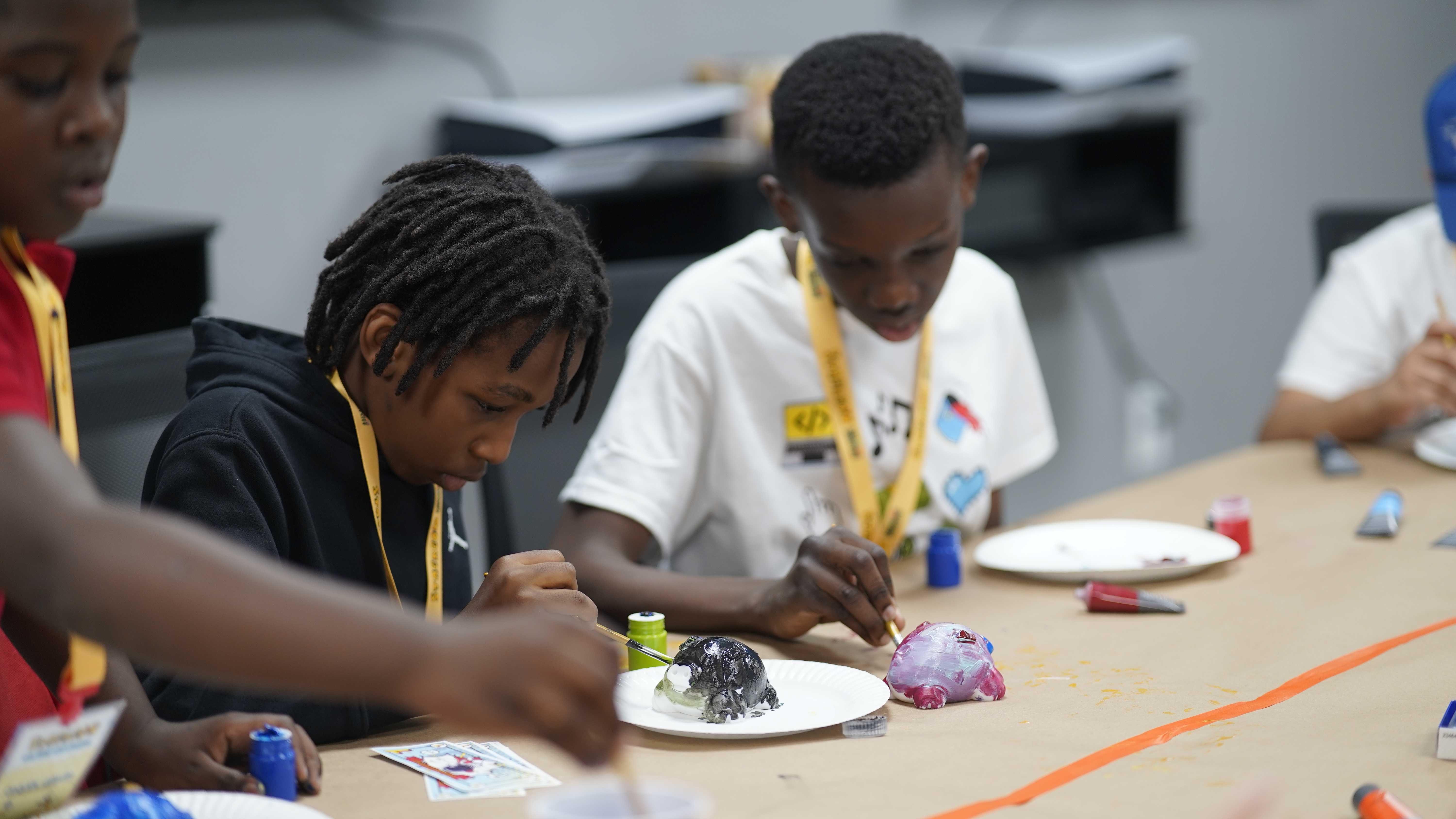 Students painting clay sculptures in an art workshop
